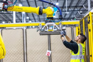 A photo of an Amazon employee working on a robot in a warehouse. 