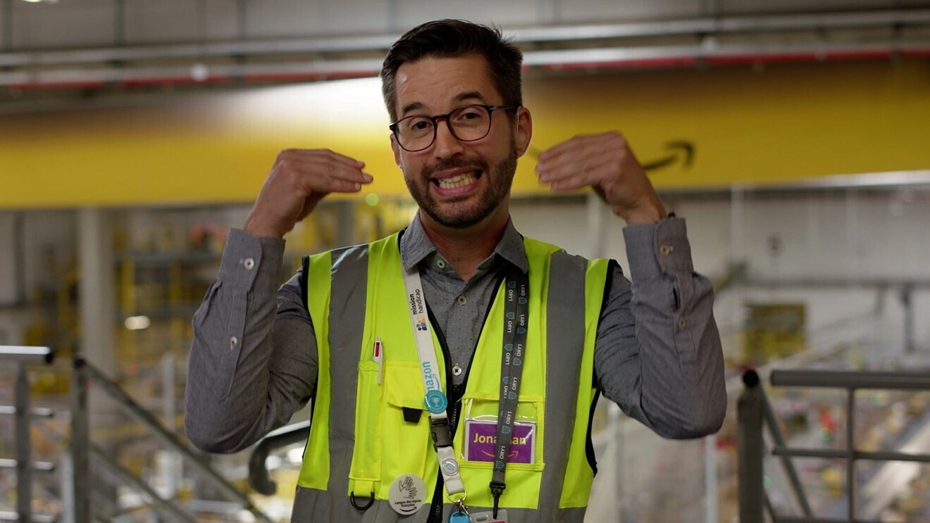 A photo of an Associate Partner at an Operations Center, speaking about Amazon providing video stations at over 200 sites to teach employees sign language.