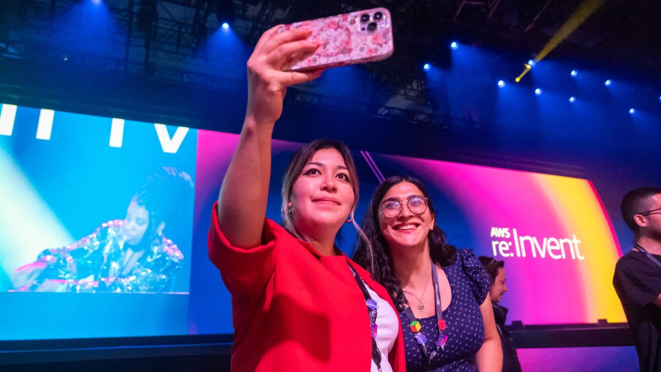 Two attendees taking a photo in the keynote room at AWS re:Invent.