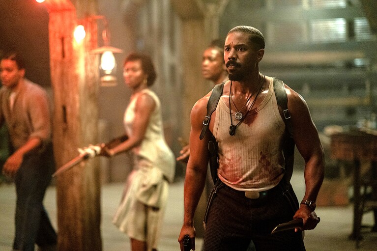 A still from Sinners, showing a tense scene with armed characters in a dimly lit industrial setting