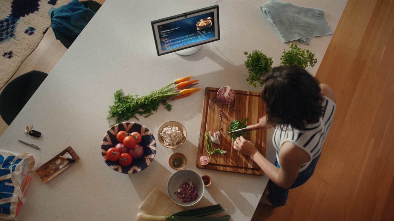 a woman follows a recipe on her echo show while chopping herbs in her kitchen