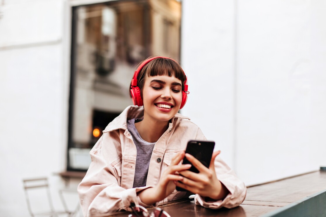 Woman listening to music on headphones while holding phone