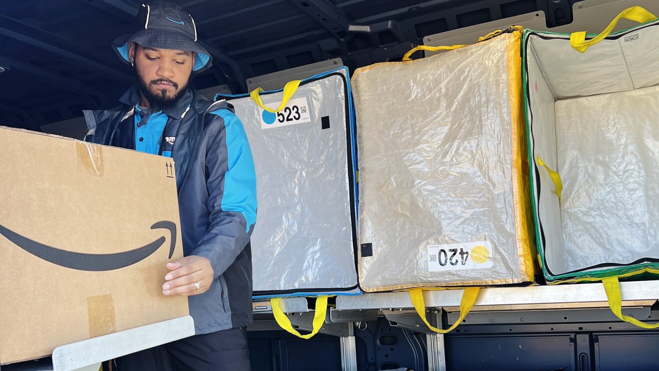 Torazz Richardson stands in the back of the delivery vehicle and picks up a delivery box.