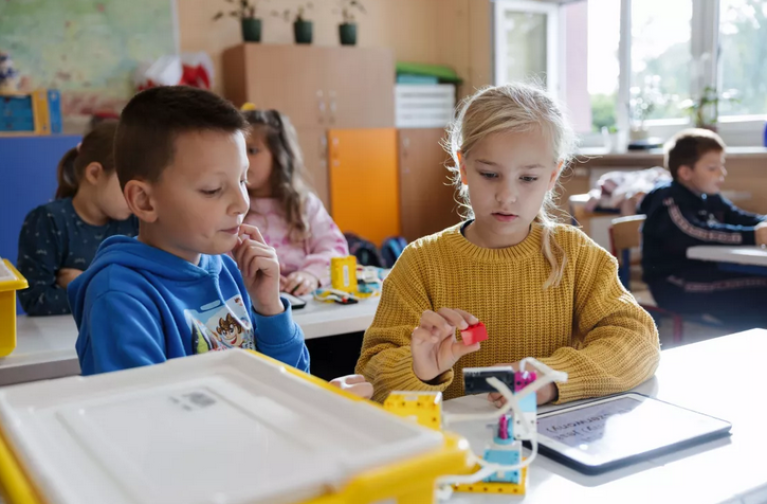 Zwei Kinder in einem Klassenzimmer arbeiten an einer Übung mit einem Tablet