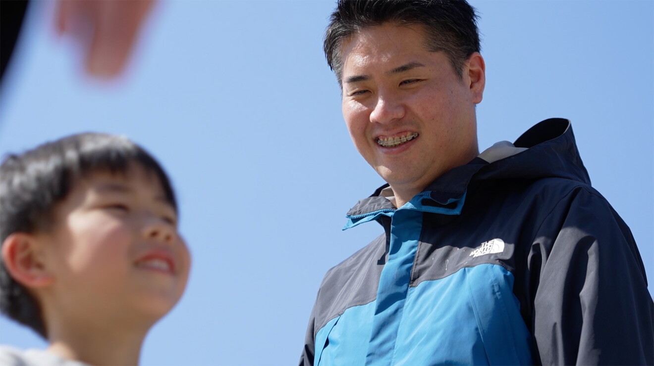 普段着姿の男性。子どもに笑顔を向けている