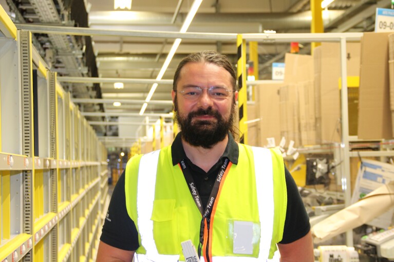 Amazon-Arbeitssicherheitsexperte Lucian Geiger mit gelber Weste im Logistikzentrum.