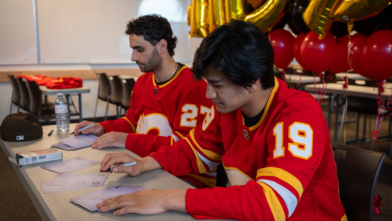 Two Calgary Flames hockey players packing and shipping Amazon boxes