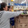 En un centro logístico están dos trabajadoras de Amazon organizando cajas. 