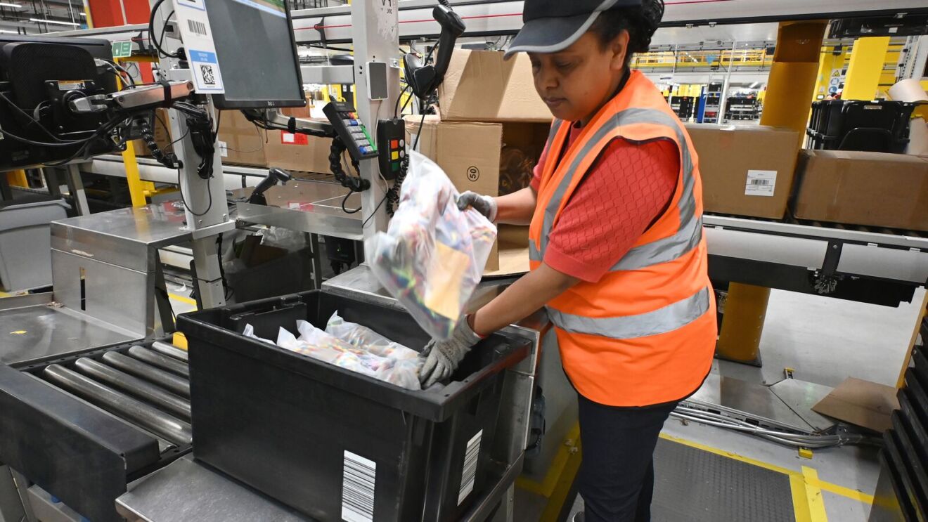Eine Logistikmitarbeiterin packt einen Artikel in eine schwarze Box.