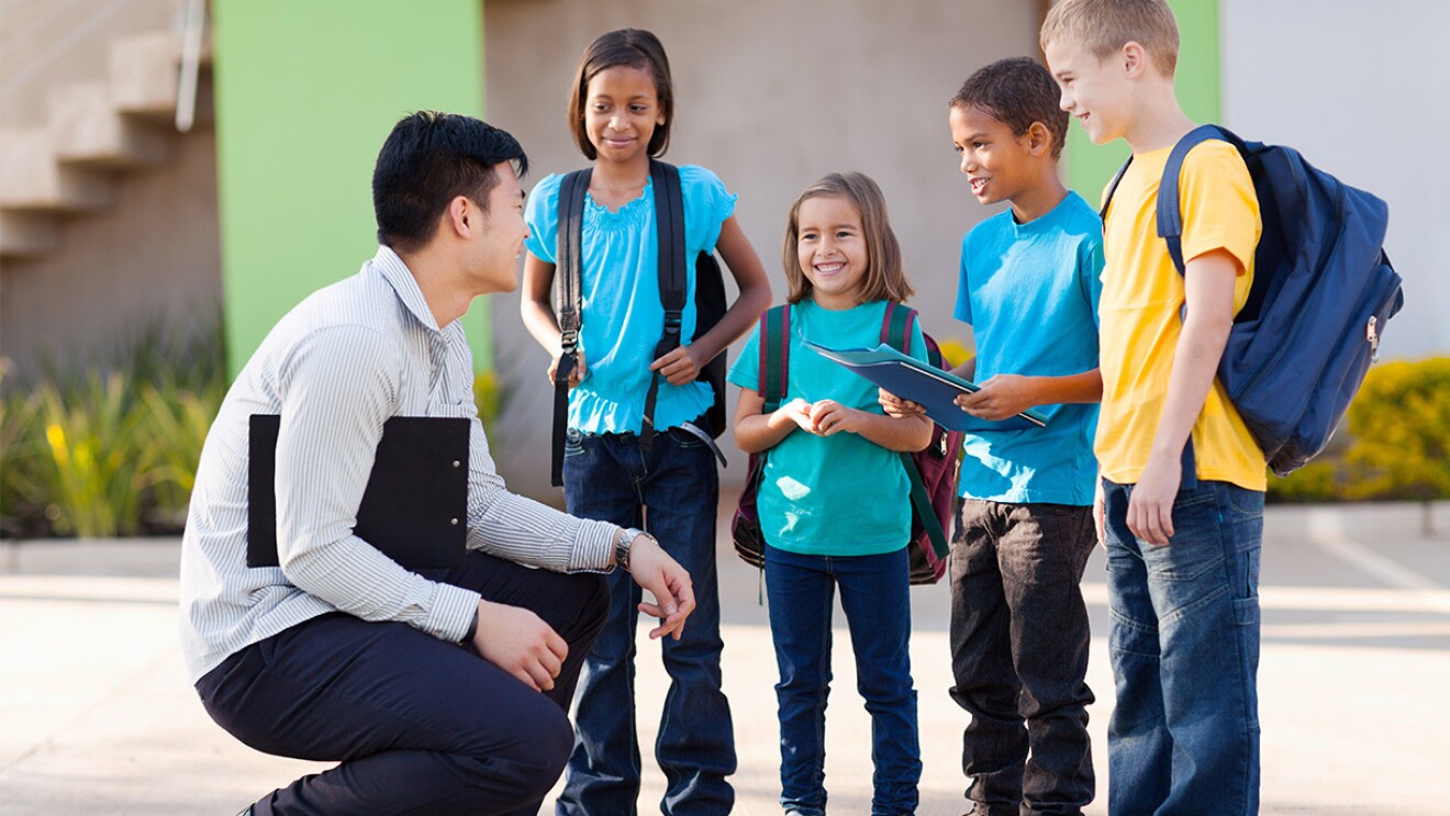 An image of a man talking to a group of young students.