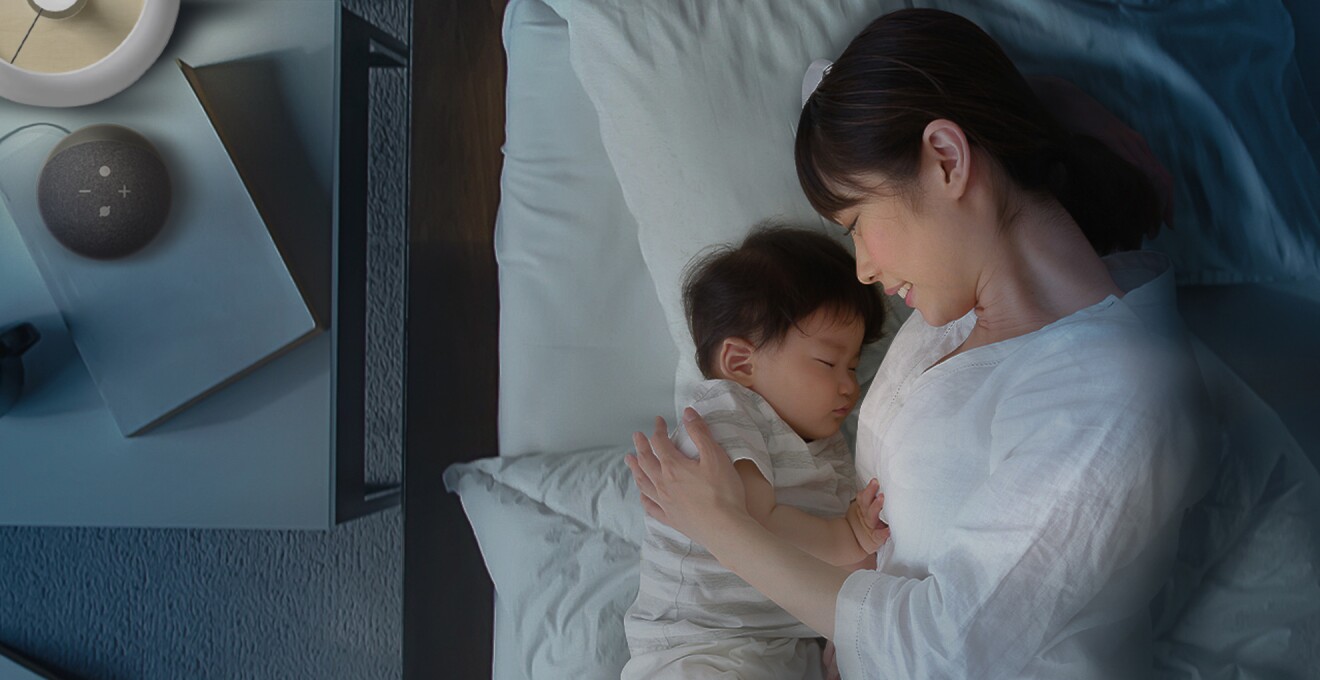 赤ちゃんの泣き声で照明が付いたので、様子を見ながらあやしているお母さんの写真