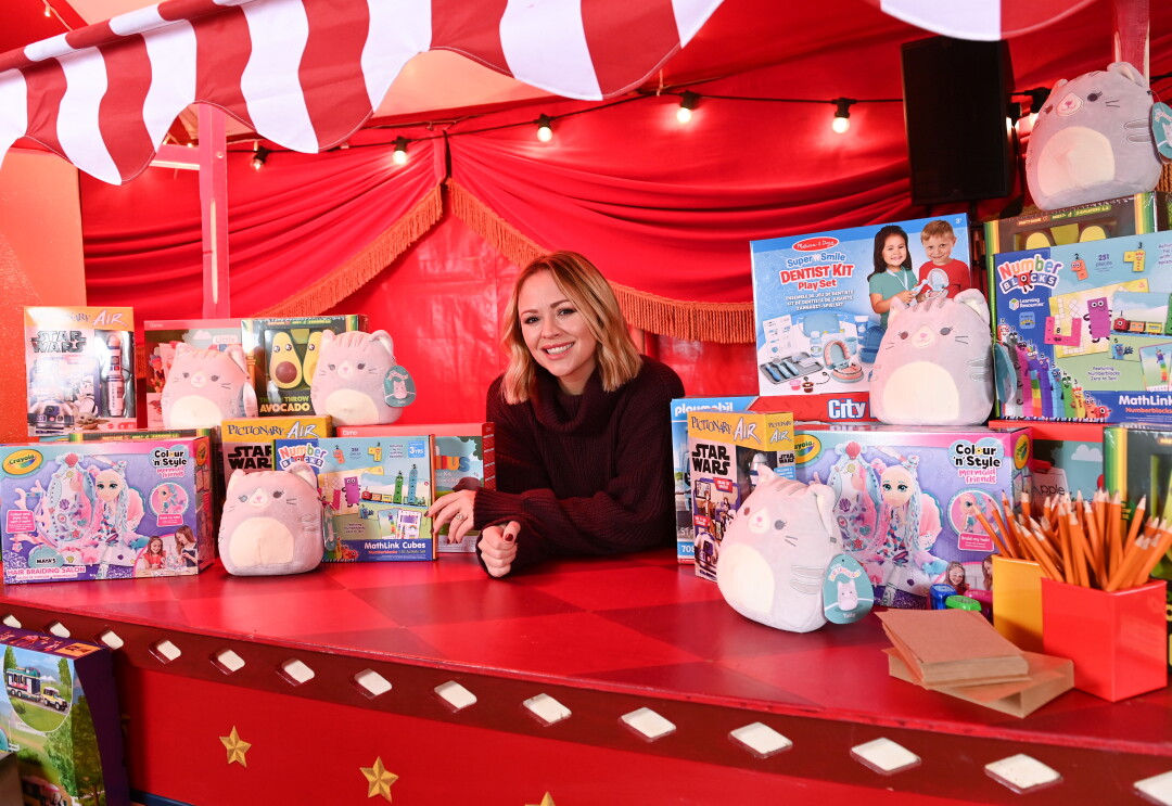 A woman at her toy stand, surrounded by toy boxes and teddies