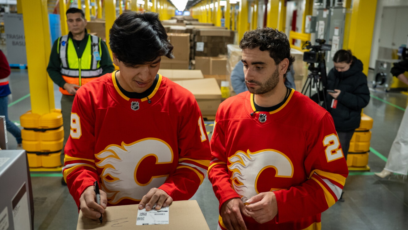 Two Calgary Flames hockey players packing Amazon boxes