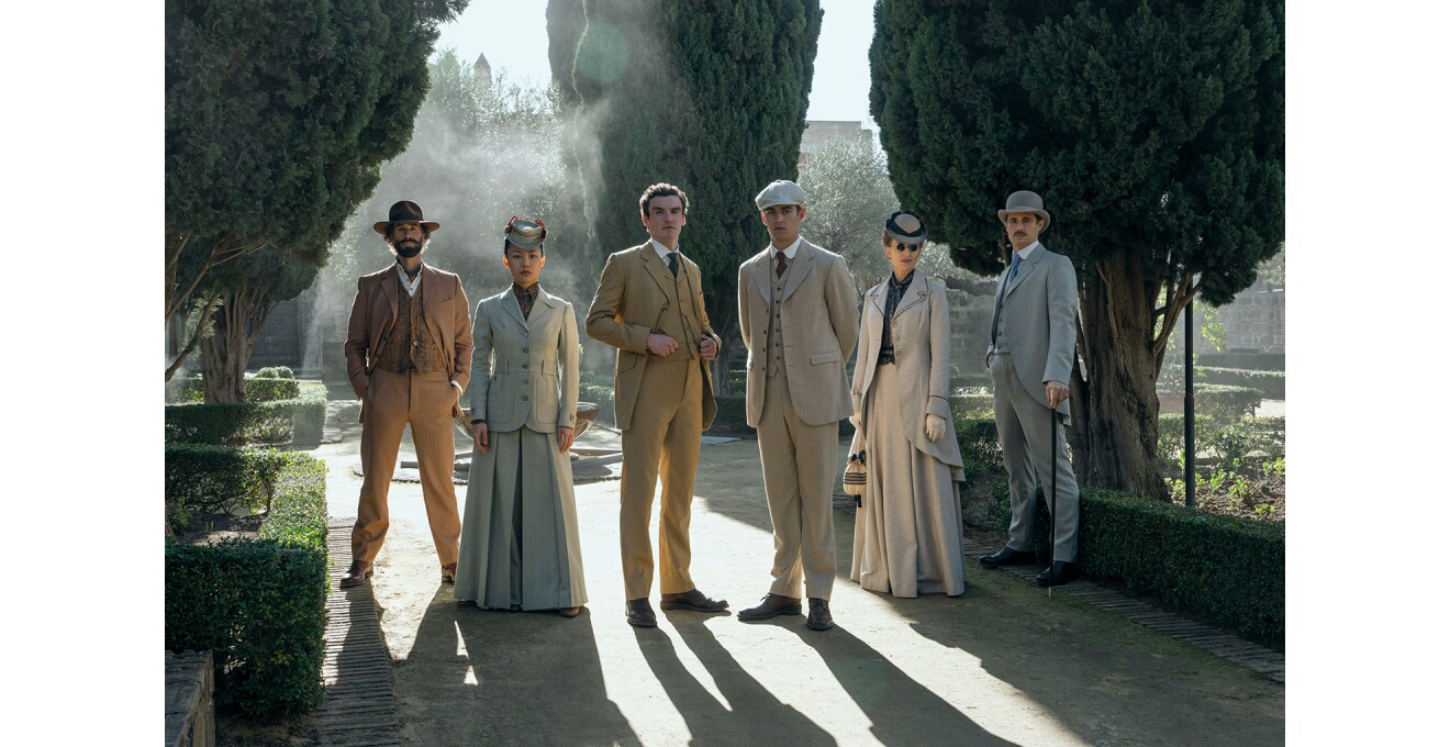 好演のような屋外で、スーツを着て並ぶ6人の人物。