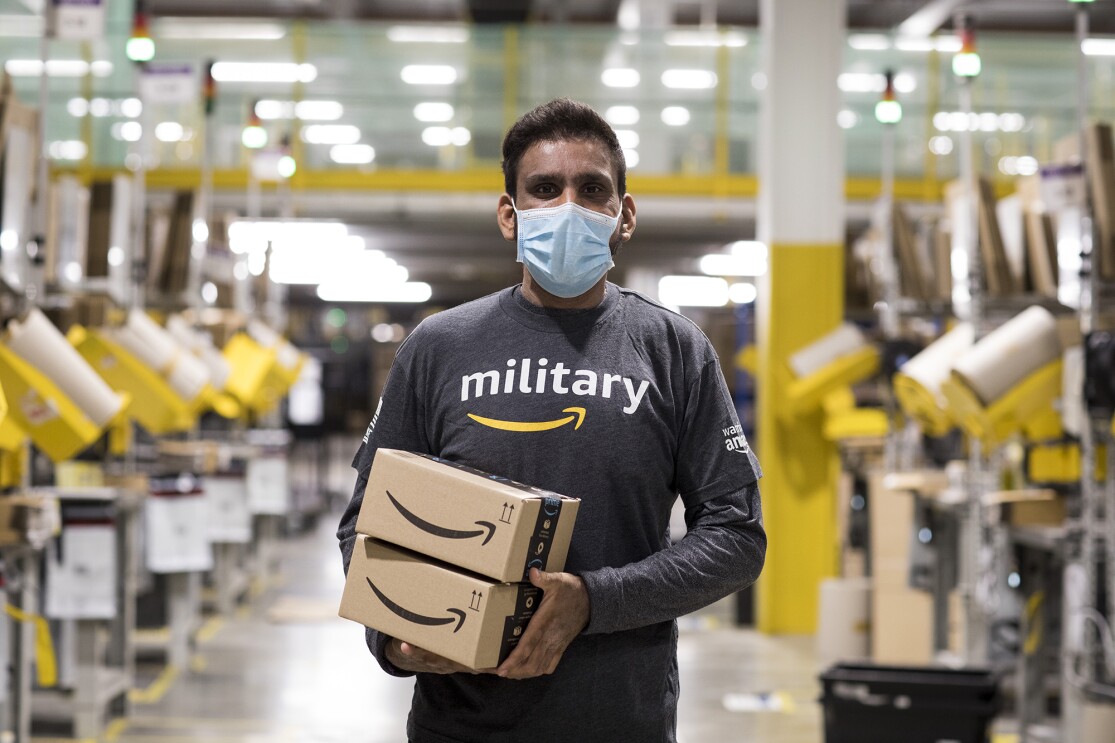 An image of an Amazon employee working at Amazon while wearing a shirt that says "military" with the Amazon logo under it.