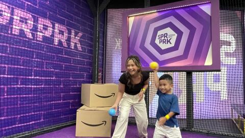 mom and kid playing at the Amazon.sg Holiday Playground with amazon branded boxes in the background