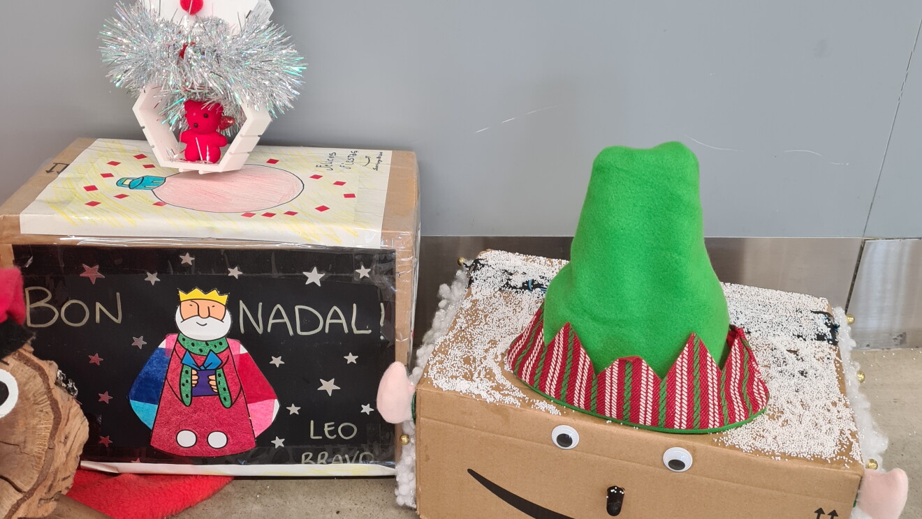 Adorno navideño de BCN1.  Un tió (tronco navideño típico catalán) y una caja con una felicitación navideña y otra caja que representa un elfo.  