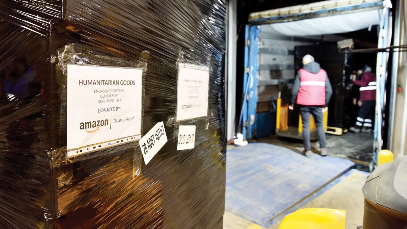 A package of donations is labeled "Humanitarian Goods" and is ready to be loaded into a truck.