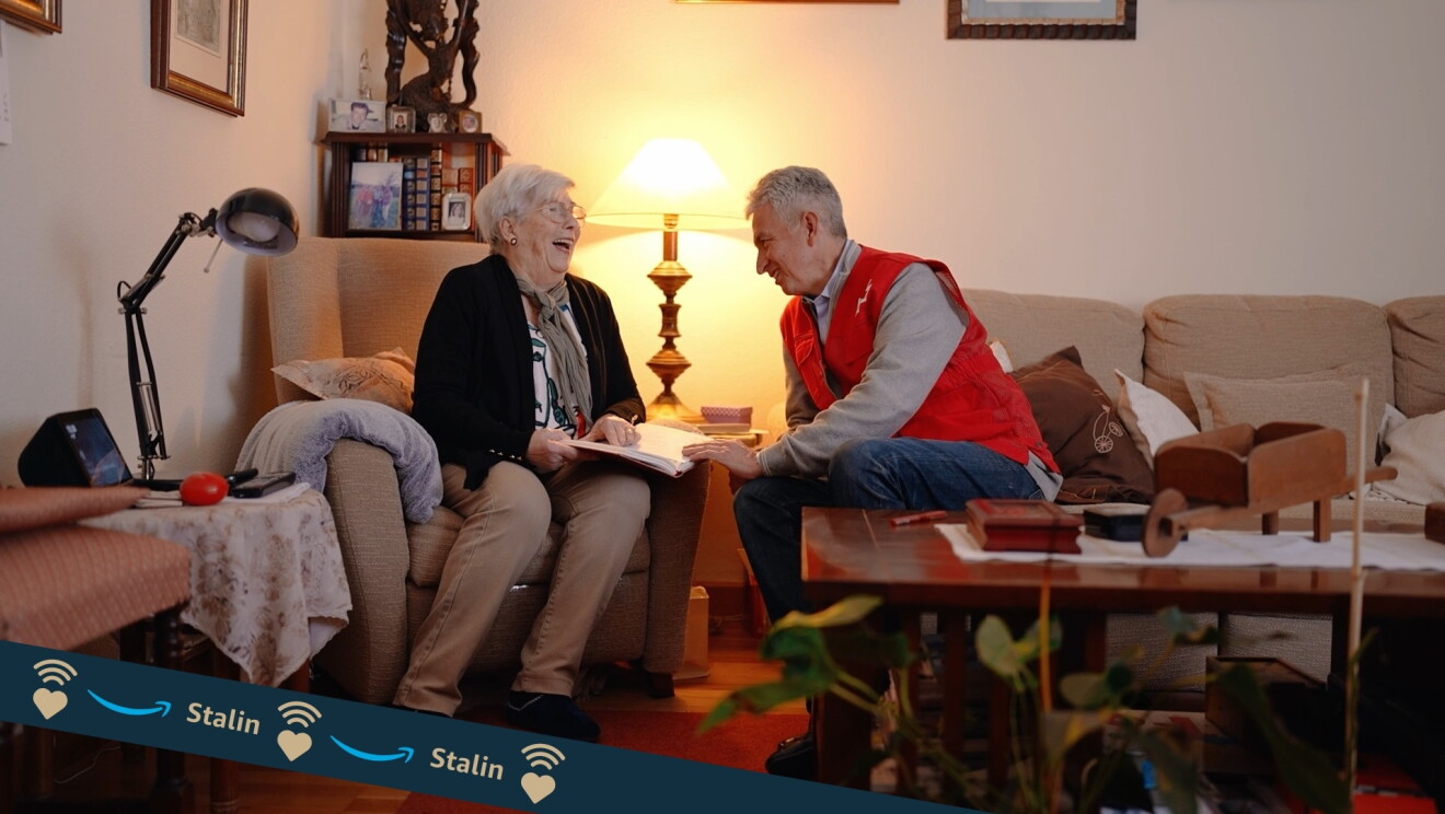 Stalin es voluntario de Cruz Roja y aparece en la foto junto con una mujer mayor en el sofá de casa de la señora. 