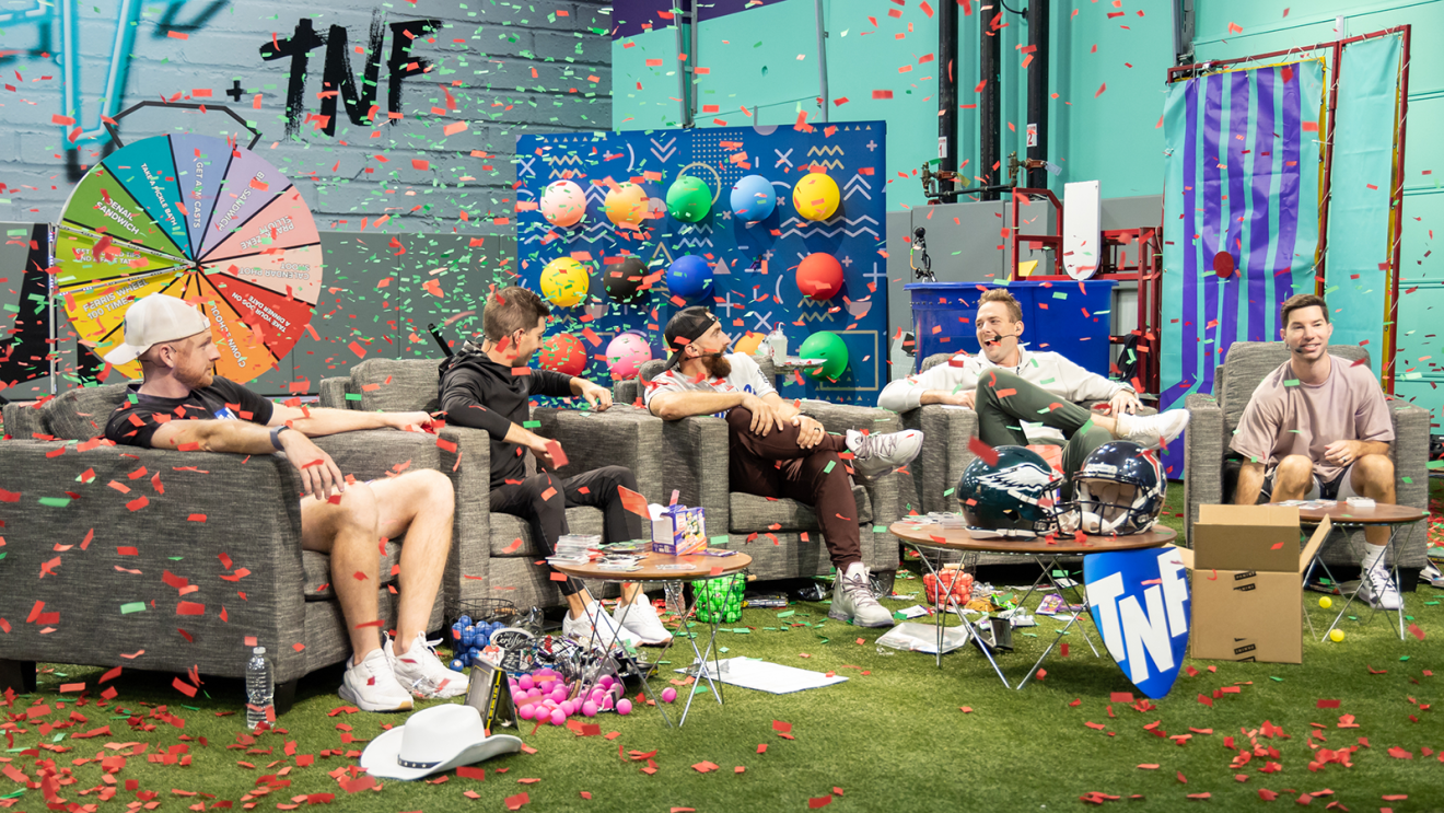 An inline photo of commentators from "TNF with Dude Perfect" sitting on couches on a set. Confetti is dropping from the sky.