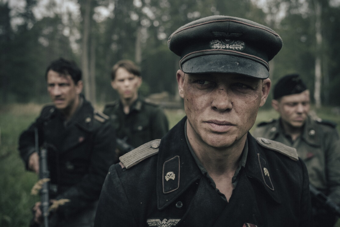Soldat im Vordergrund an der Front im Hintergrund drei seiner Kameraden.