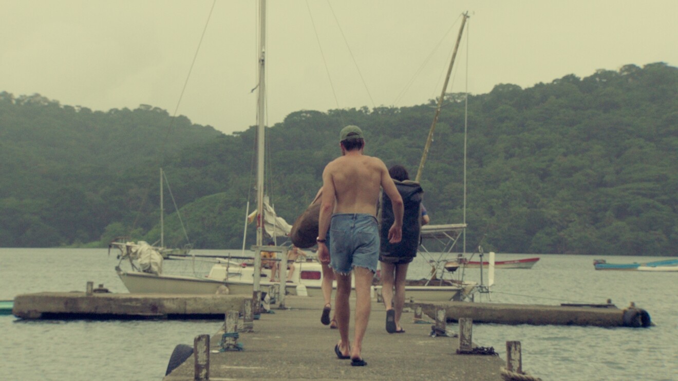 Three people walking on the dock looking ahead at some boats