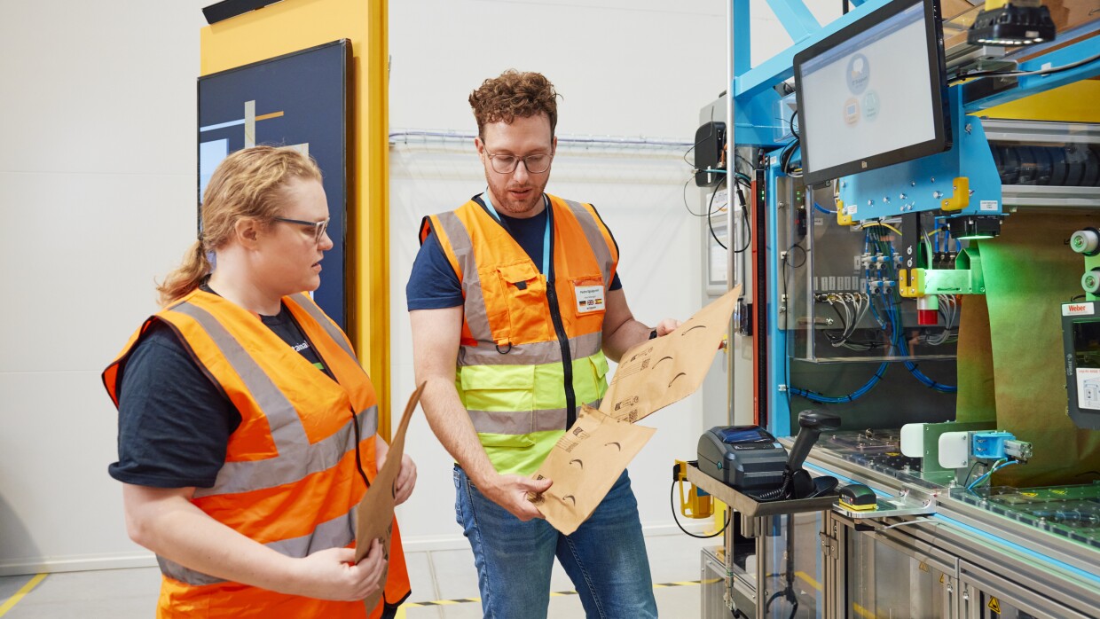 Dos trabajadores de Amazon en un centro logístico inspeccionando unos sobres.