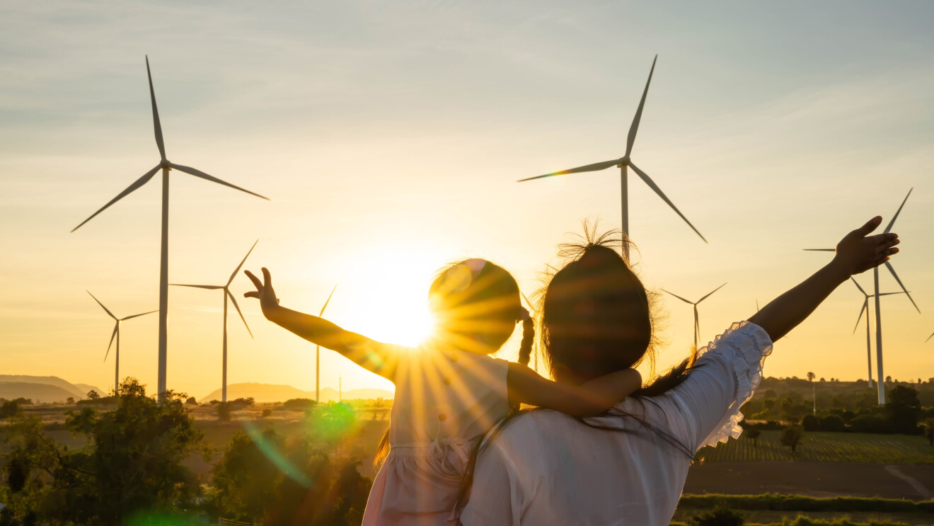 family embrace sunlight in front of wind turbines