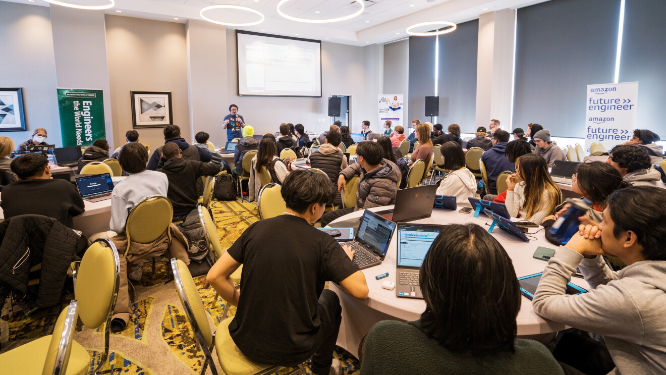 Students sitting in a conference room listening to a presenter at an Amazon Future Engineer event.