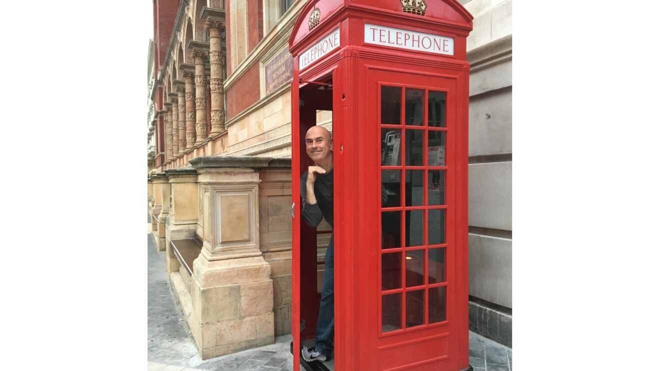 Paul posing in a red telephone box in London.