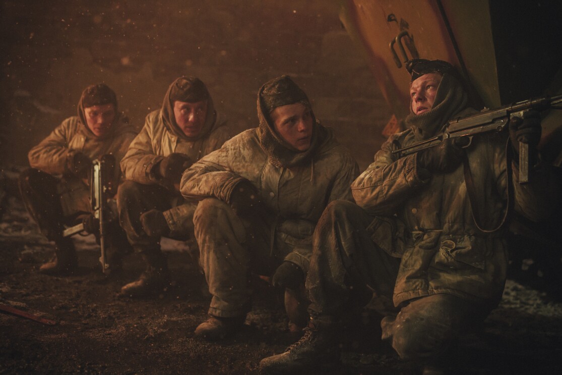 Soldaten in Winterausrüstung drängen sich unter rauen Bedingungen zusammen.