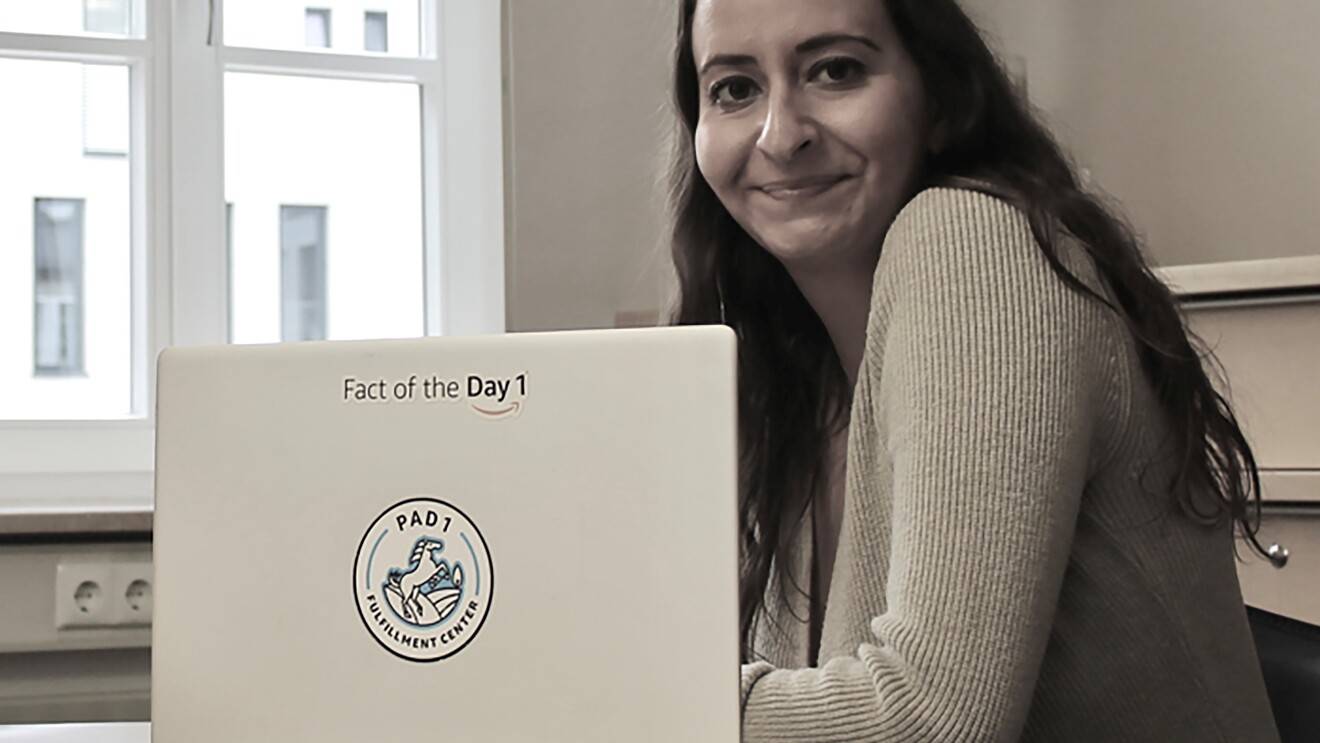 Eine junge Frau mit langen dunklen Haaren vor einem Laptop