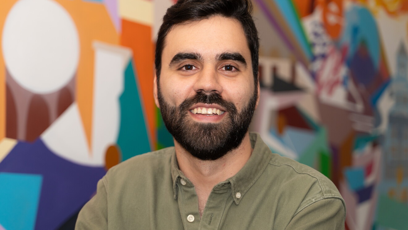 Alexandre Rodríguez, New Account Manager, Channels Sales. Mirando a cámara con una camisa color verde camuflaje. Tiene el pelo negro, barba y bigote. 