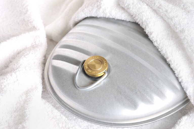 白い毛布にくるまれているブリキ製の湯たんぽ