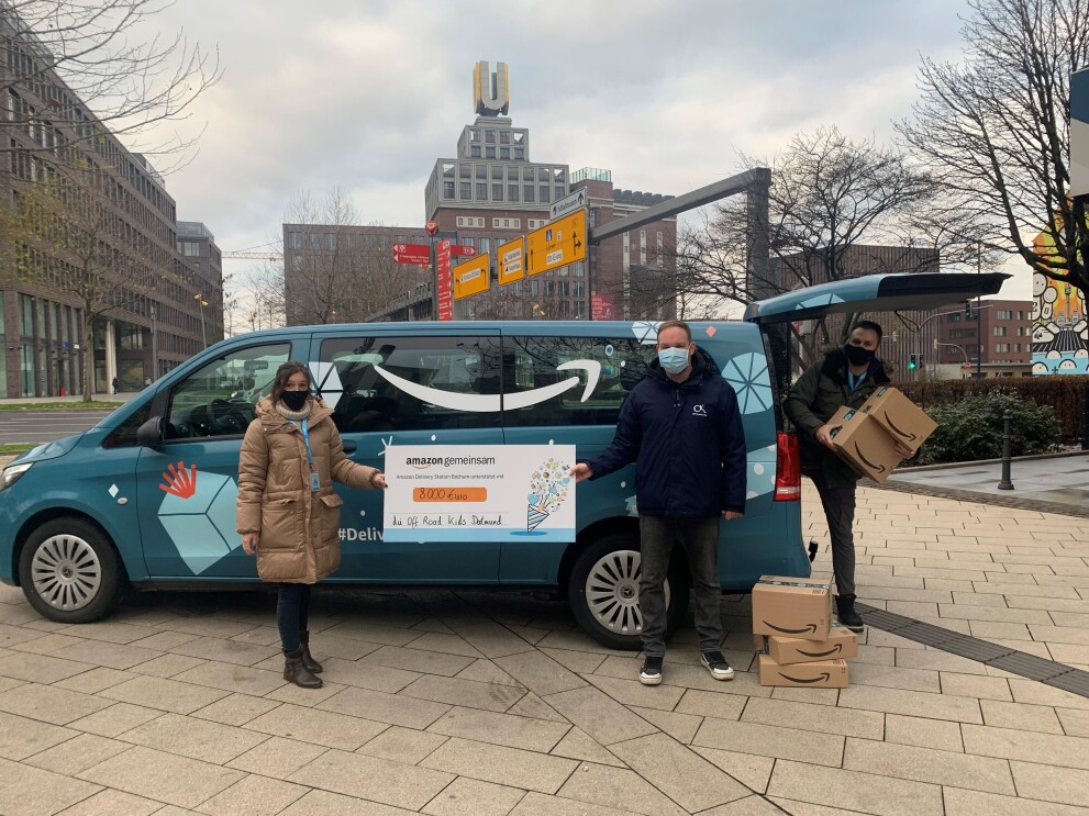 Amazon Van mit Mitarbeitern und Spendenscheck.