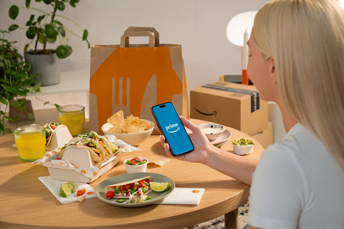 Una mujer sentada en una mesa con el teléfono en la mano. 