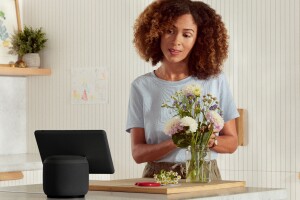 An image of a woman in her house interacting with Alexa through an Echo device. 