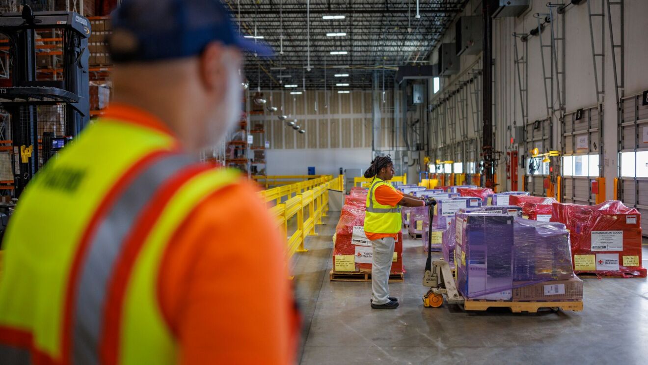 Warehouse workers in safety vests handling pallets of supplies