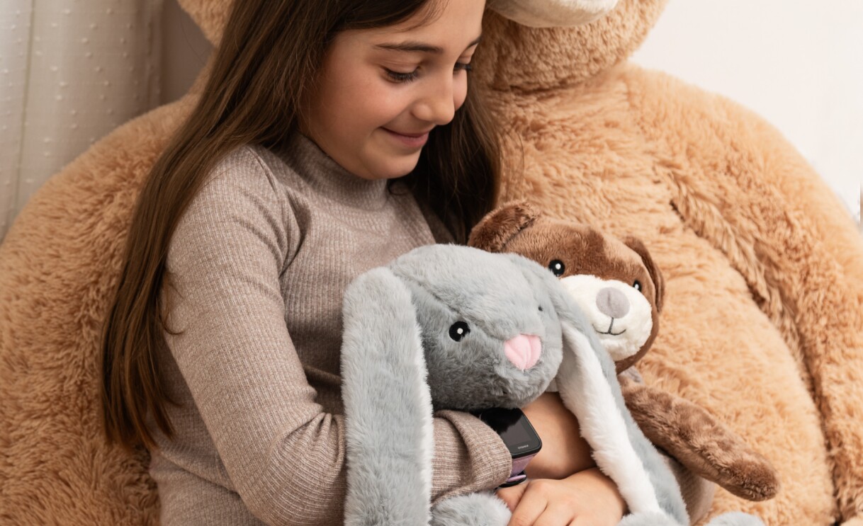 Une petite fille serrant dans ses bras deux peluches