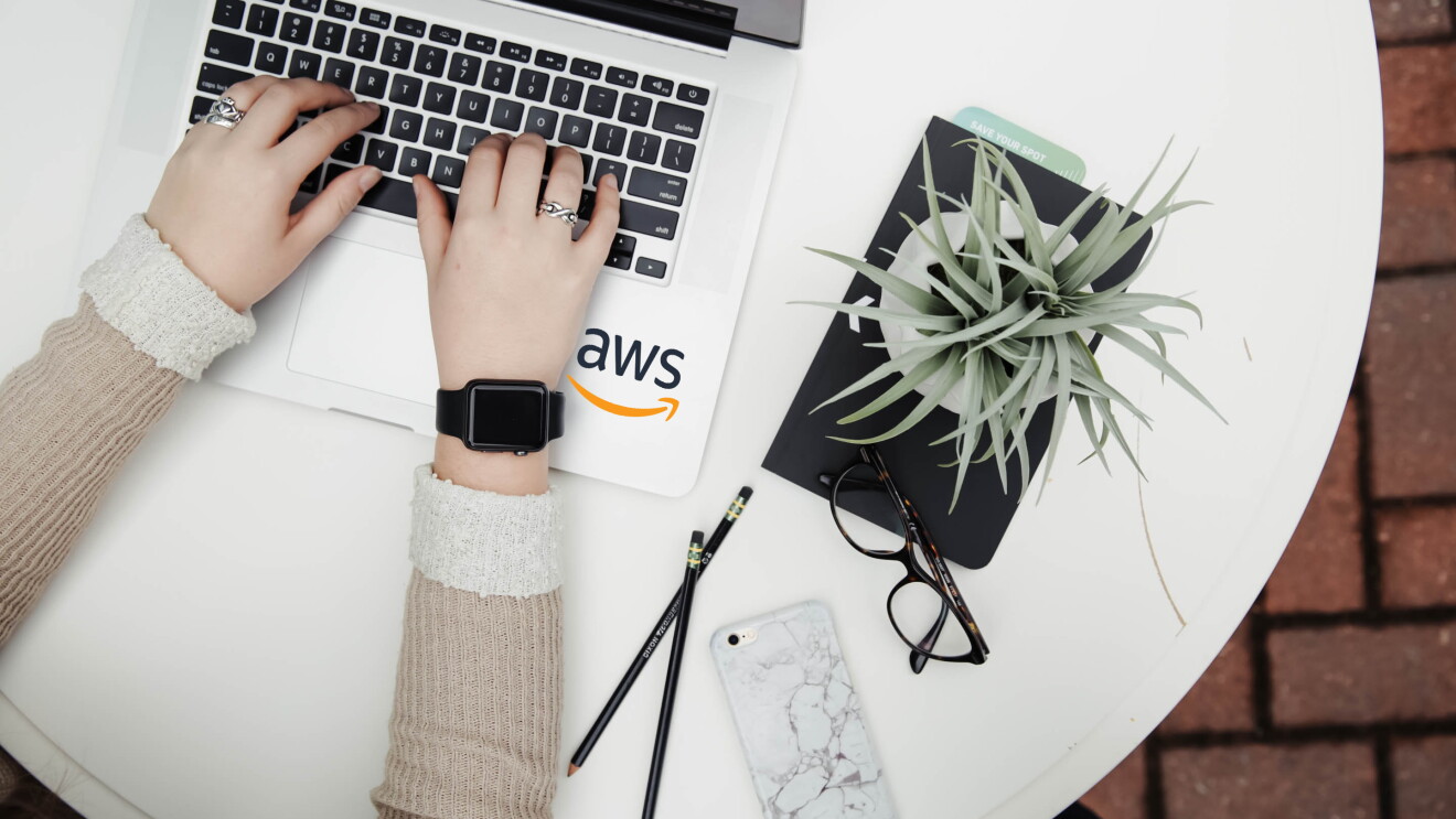 AWS logo seen in the laptop and a woman's hands seen using the laptop
