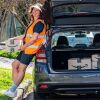 Amazon Delivery Partner and mid-career student Angie James leaning against her car. Its boot is filled with Amazon packages.