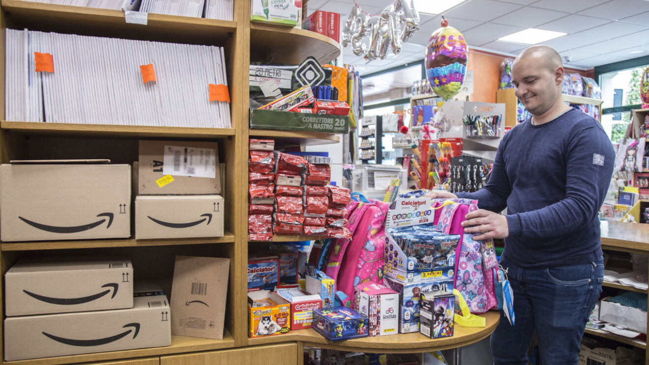 Andrea Locatelli all'interno della cartoleria Teresa di Chiuduno, circondato da prodotti, oggetti regalo e pacchi Amazon.