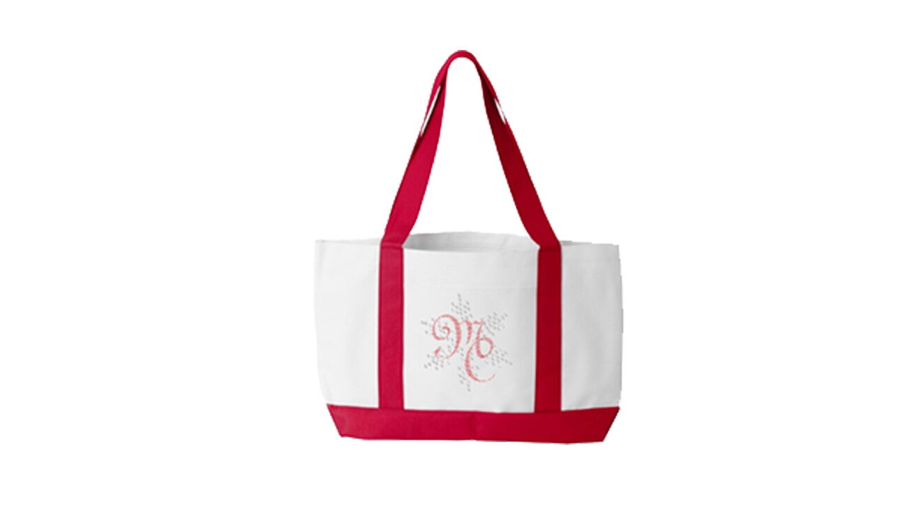 A white tote back with red straps. The front of the tote has red lettering that reads "MC."