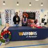 Two Amazon employees standing at a Warriors at Amazon desk surrounded by poppies and Canadian flags