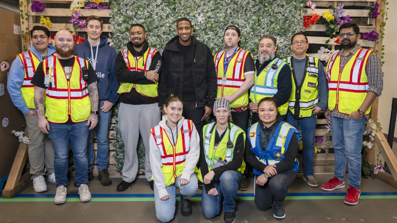 A photo of Quarterback Michael Penix, Jr. and eleven Amazon employees.