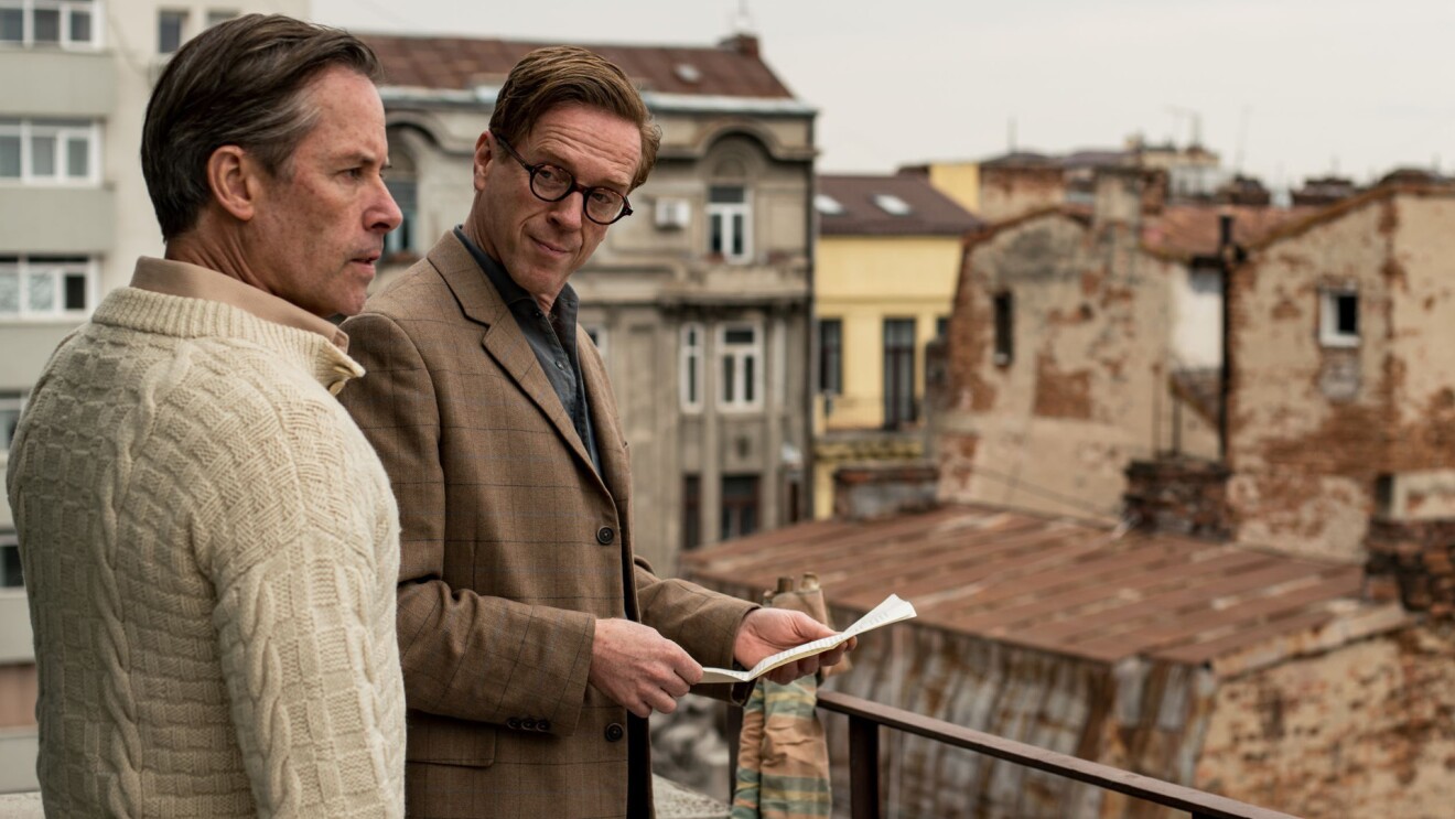 A scene of "A Spy Among Friends" showing two men in a balcony. 