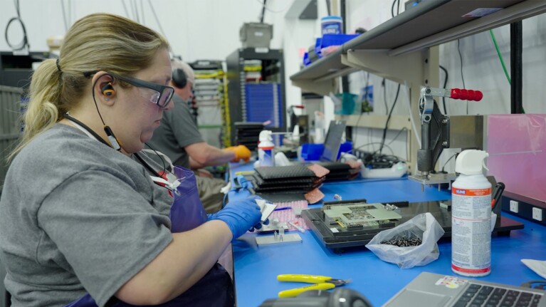 A photo of an AWS failure analysis lab technicians removing components from a Nitro Card to assess physical damage.