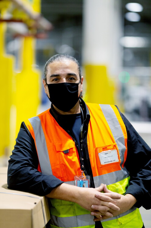 Antonio Kanaris - wearing a facemask and hi-vis in a fulfilment centre.