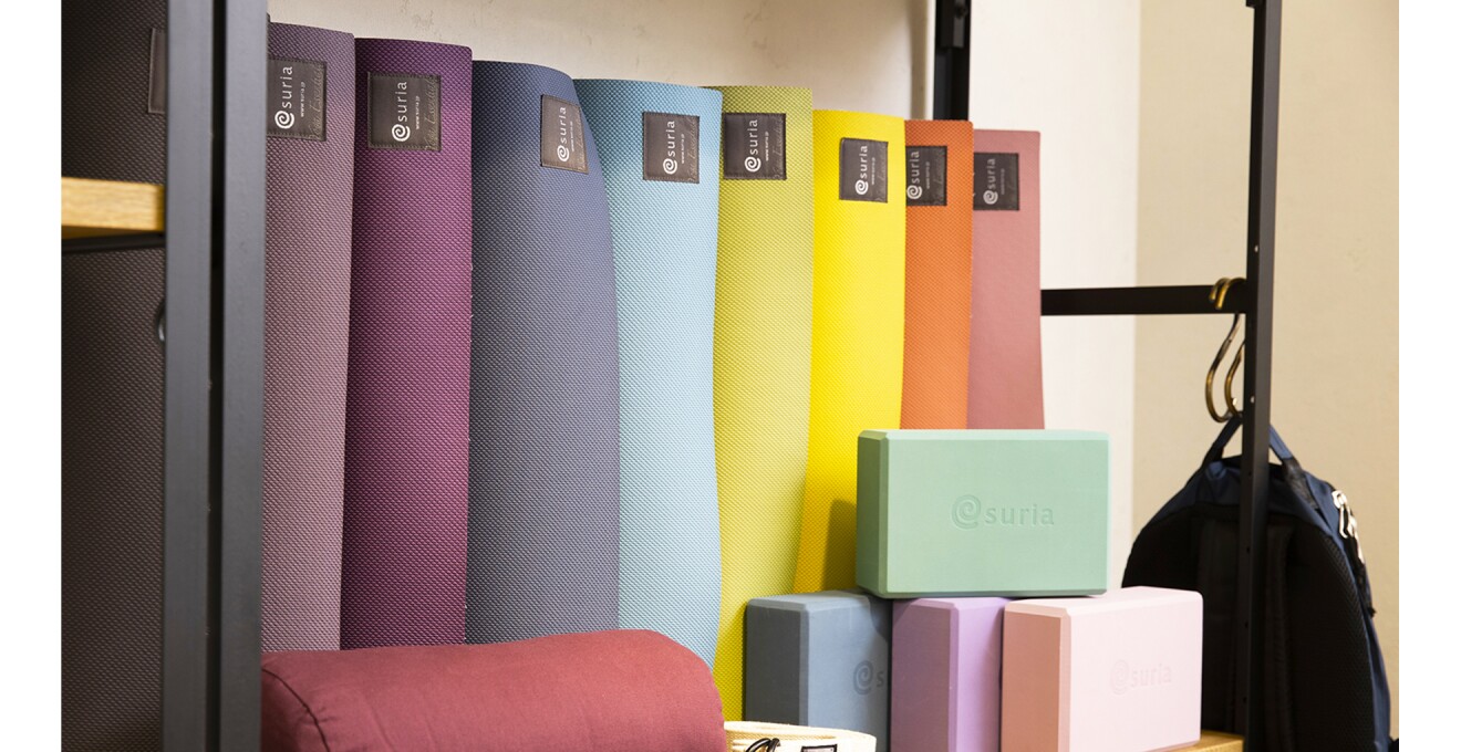 商品が並ぶ棚の奥にカラフルな色展開のヨガマットが立てかけられている。