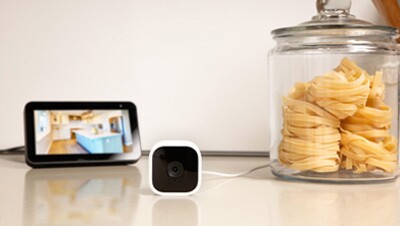 Un dispositivo Blink con cámara y monitor en la mesa de una cocina.